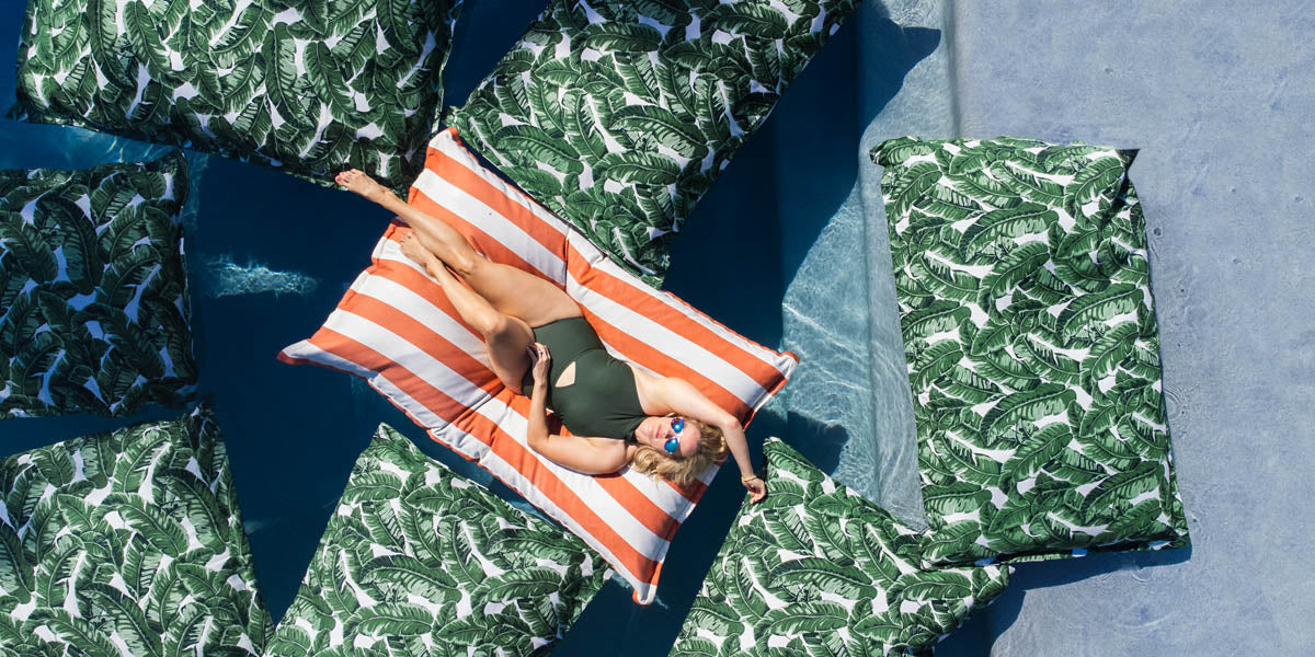 Woman on a Laze Pillow in the pool, surrounded by other Laze Pillows