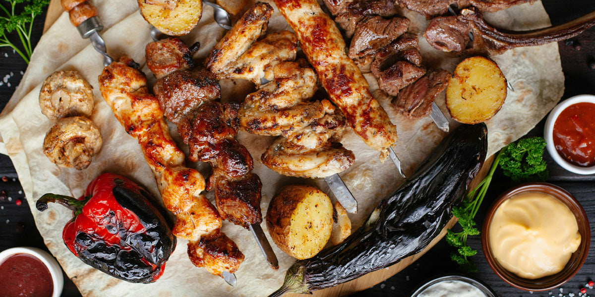 Meat kebabs laid out on table with grilled vegetables