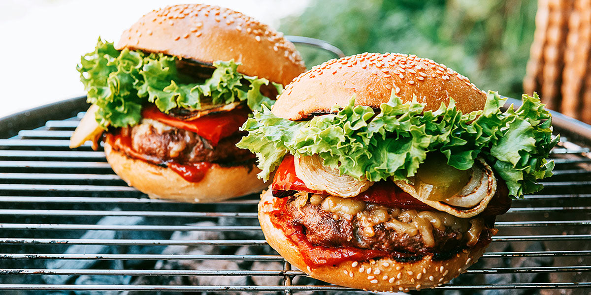 Fully loaded hamburgers sitting on the grill