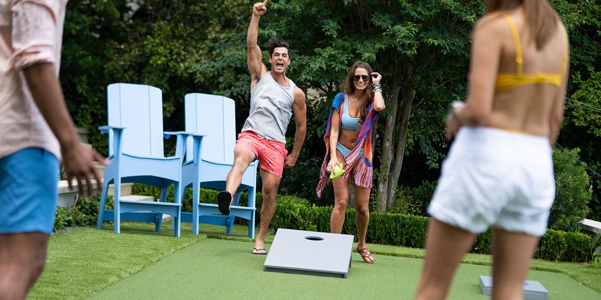 Friends having fun playing cornhole outside