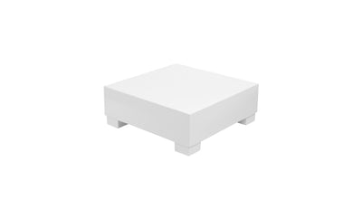 A plain white square block with four small legs, resembling a minimalist table from Ledge Loungers Signature Collection, stands against a stark white background.