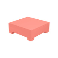 The Ledge Lounger Signature Coffee Table, a coral-colored square block with four short legs, offers minimalist elegance. Part of our Signature Collection, it’s perfect for stylish outdoor lounging by the pool, set against a plain white background.
