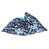 The Laze Pillow by Ledge Lounger is a large, soft bean bag featuring a black and white tie-dye pattern with a touch of blue, ideal for outdoor lounging or as a floating pool cushion, shown on a plain white background.