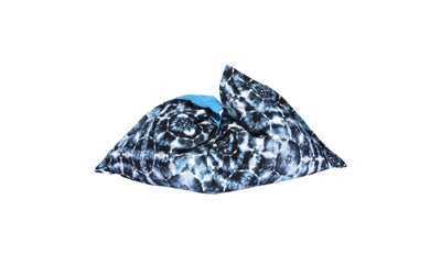 The Laze Pillow by Ledge Lounger is a large, soft bean bag featuring a black and white tie-dye pattern with a touch of blue, ideal for outdoor lounging or as a floating pool cushion, shown on a plain white background.