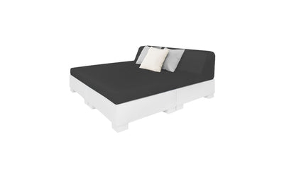 The Affinity Square Sunbed with Backrest Cushion by Ledge Lounger showcases a sleek black mattress on a white block-style base, ideal for poolside lounging. Accentuated with three pillows in black, white, and gray, it complements the clean aesthetic of any outdoor space.