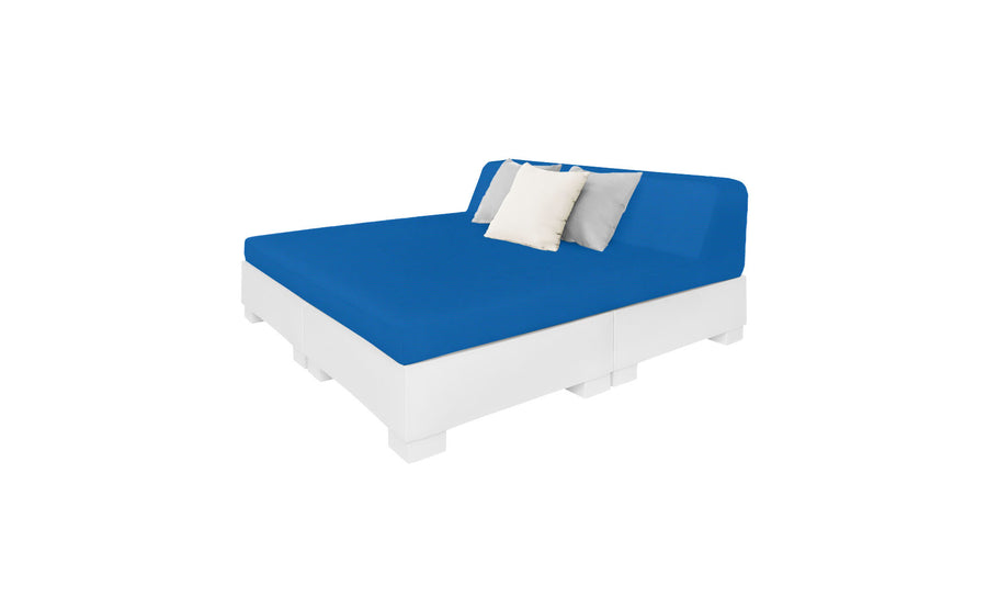 The Affinity Square Sunbed with Backrest Cushion by Ledge Lounger features a blue mattress, white and gray pillows, and a minimalist white platform. Ideal for poolside relaxation, its sleek design contrasts elegantly with a plain white backdrop to enhance outdoor spaces with simplicity and style.