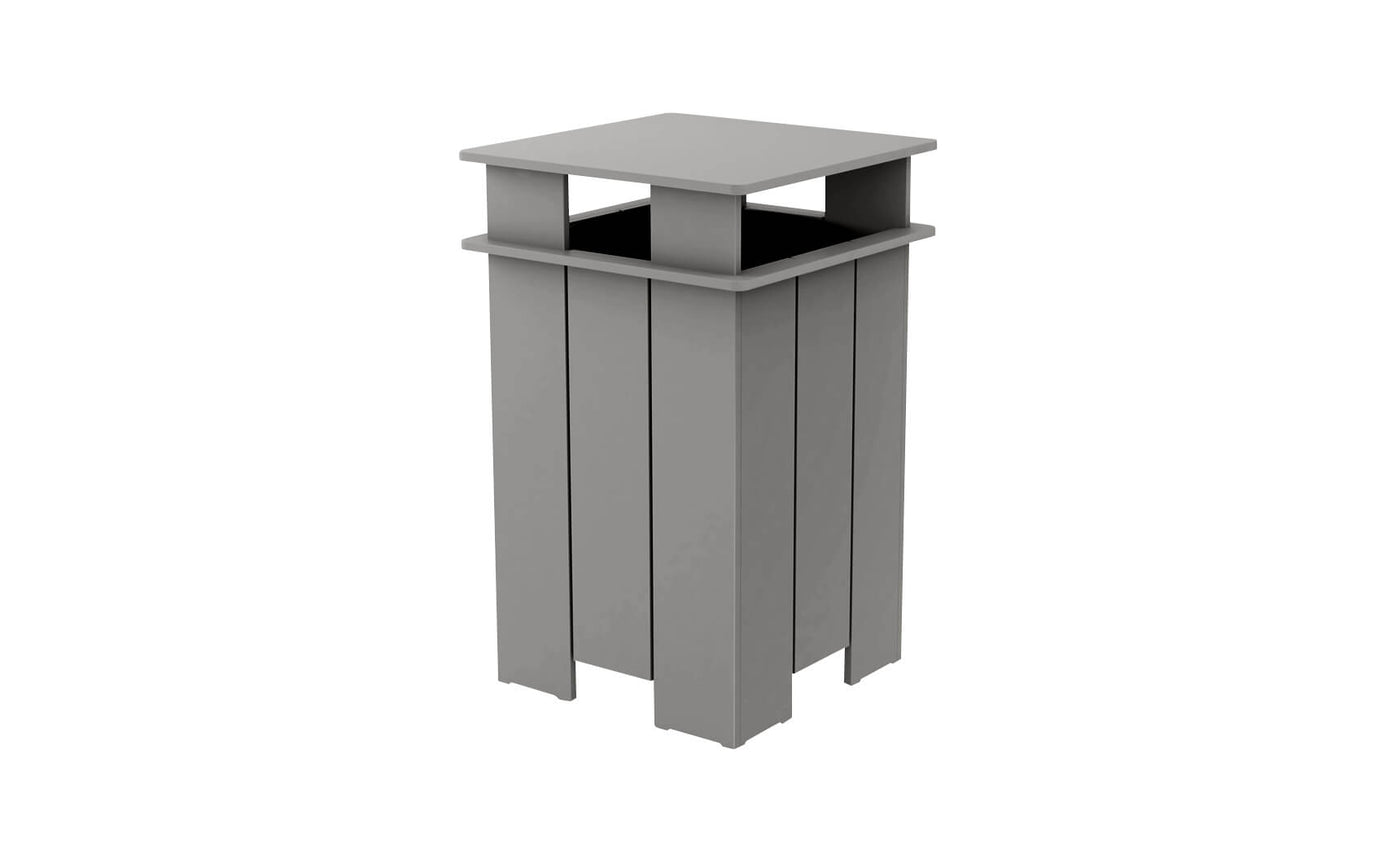 The Mainstay Trash Bin by Ledge Lounger is a tall, rectangular, gray outdoor trash can. It features a flat top and open sides with vertical slats in a modern, minimalist design. Crafted from UV stable materials, it ensures lasting durability.