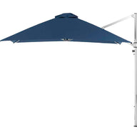 The Ledge Lounger Ultra Cantilever Umbrella - 10 Square in navy blue features a metallic stand and adjustable arm, paired with a rechargeable light. Its wide open canopy provides ample shade while the stand is set aside.