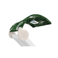A Signature Chaise Shade from Ledge Lounger is partially covered with tropical leaf-pattern fabric in green shades, and it includes a convenient integrated control panel on one side.