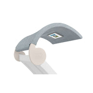 Introducing the Signature Chaise Shade by Ledge Lounger: a modern light blue upholstered lounge chair with a curved backrest and sleek white frame featuring a wave design, ideal for relaxing by your media viewing window. An intricate label details the backrest.