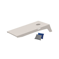 A Ledge Lounger Cornhole board with a beige rectangular surface and a round hole features two small blue and gray bags nearby, part of this fun bean bag toss set.