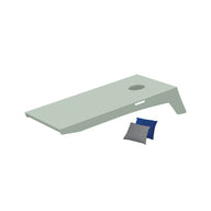 The image shows a light green Cornhole board by Ledge Lounger, featuring a hole on the upper right and angled for an engaging Bean Bag Toss. A blue and gray bean bag rest beside it, part of this portable set.