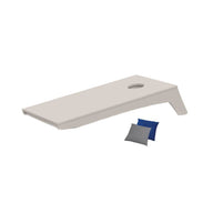 The Ledge Lounger Cornhole set includes a minimalist board design with an angled setup and a hole near one end, accompanied by two bean bags in blue and gray ready for tossing.