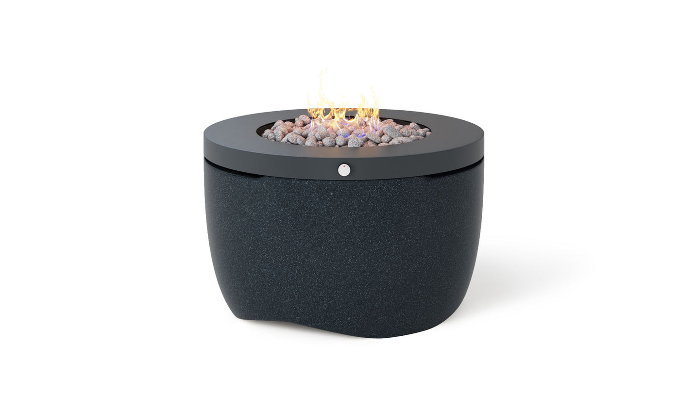 The Halo Firepit by Ledge Lounger is a modern, round, black propane fire pit featuring a smooth, speckled surface with a pivot-glide lid. Flames elegantly rise above decorative rocks, creating an enhanced outdoor ambiance against a simple white background.