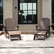 Two Legacy Adirondack by Ledge Lounger chairs with footrests sit on a patio in front of a modern building, ideal for gatherings. Behind them are large windows and stairs, while planters with purple flowers and trimmed hedges add to the inviting outdoor setup.