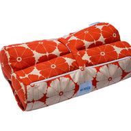 The Laze Hammock yoga mat bag from Ledge Lounger, featuring a red floral quilted design with white flowers and a blue label, is perfect for outdoor adventures. Made from marine-grade fabrics, it includes a convenient handle and rolls up securely with a strap.