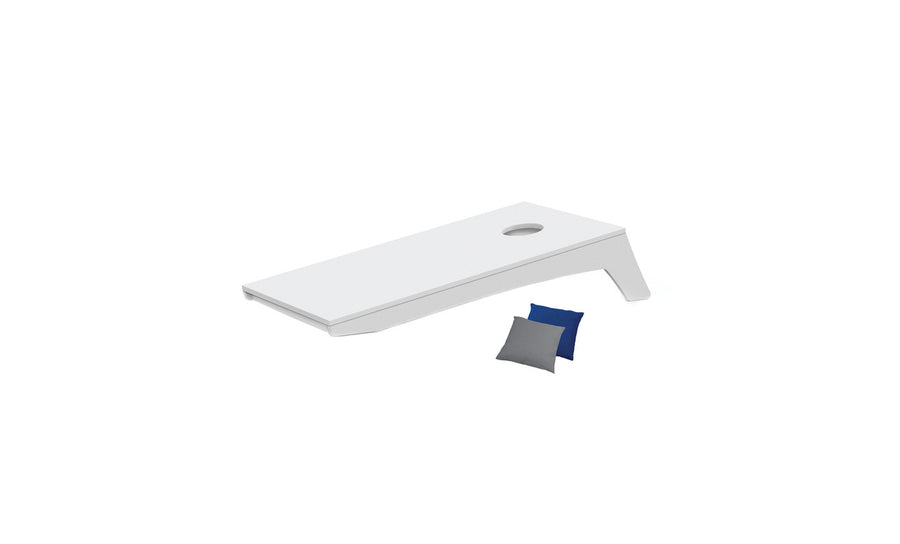 The Ledge Lounger Cornhole is a minimalist, portable set featuring a sleek board with a single hole against a white background. It comes with two small bean bags—one blue and one gray—ideal for an impromptu toss game.