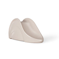 The Signature Slide by Ledge Lounger is a beige, minimalist indoor childrens slide made of plastic with smooth, curved edges. It includes top side handles for safety and stability, resembling a modern pool slide design.
