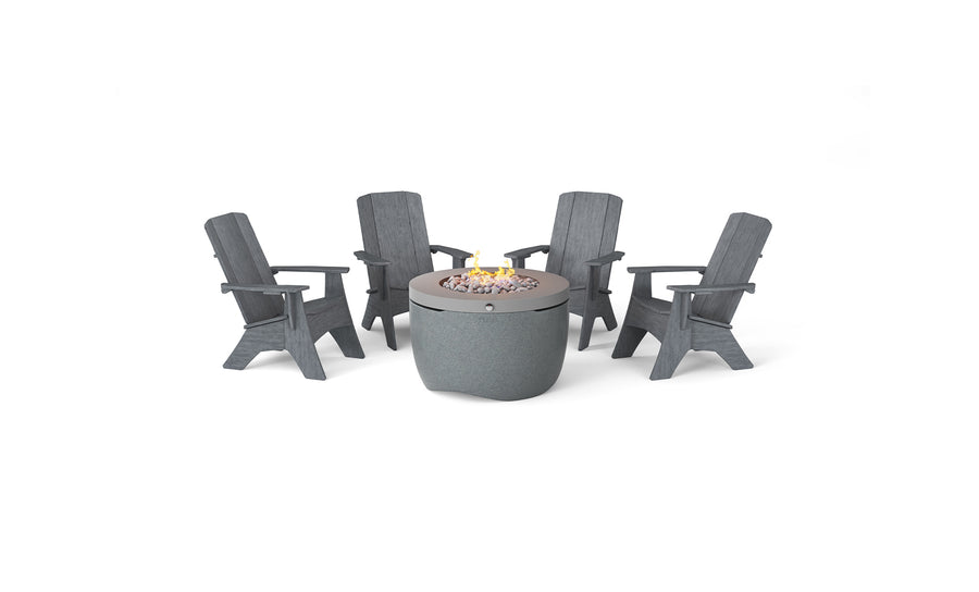 The Halo Aglow Bundle by Ledge Lounger features four dark gray Adirondack chairs around a round gray outdoor gas fire pit, embellished with small stones and a gentle central flame, set against a plain white background.