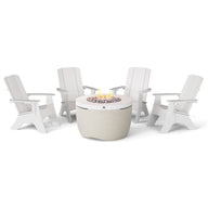 The Halo Aglow Bundle by Ledge Lounger features four white Adirondack chairs encircling a gray round fire pit table, complete with a burning flame and decorative stones, all set against a plain white backdrop.