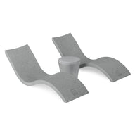 The Ledge Lounger Signature Chaise and Affinity Side Table In-Pool Set features two modern gray wave-shaped loungers with a side table between them, displayed on a white background.