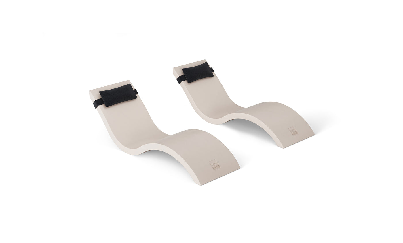 The Outdoor Escape In-Pool Furniture Bundle by Ledge Lounger, featuring two sleek chaise lounges with wave-like designs and black headrests, creates a stylish statement against a plain white background.