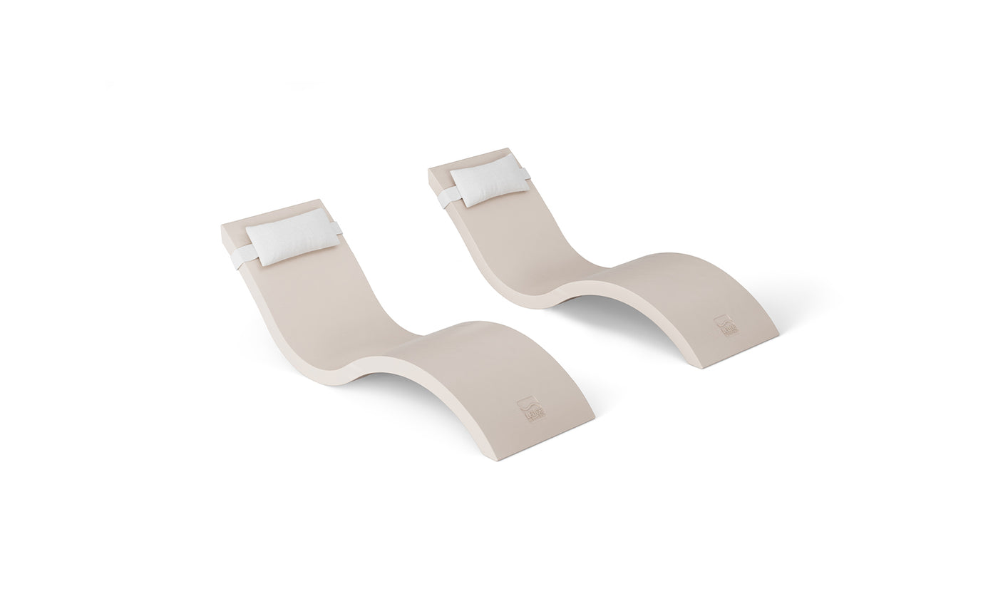 A pair of modern, beige, wave-shaped Signature Chaise loungers with white headrest pillows from the Ledge Lounger Outdoor Escape In-Pool Furniture Bundle are set against a plain white background, highlighting their sleek and minimalist design.