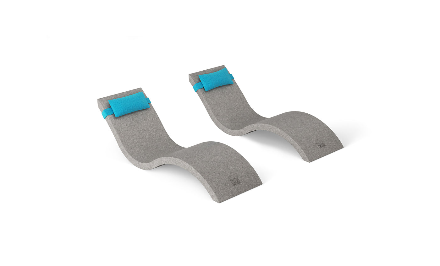 Two contoured Ledge Lounger Signature Chaise lounge chairs feature smooth curves, gray concrete finish, and blue headrest pillows. Placed on a white background, they offer a modern design, perfect as part of the Outdoor Escape In-Pool Furniture Bundle.