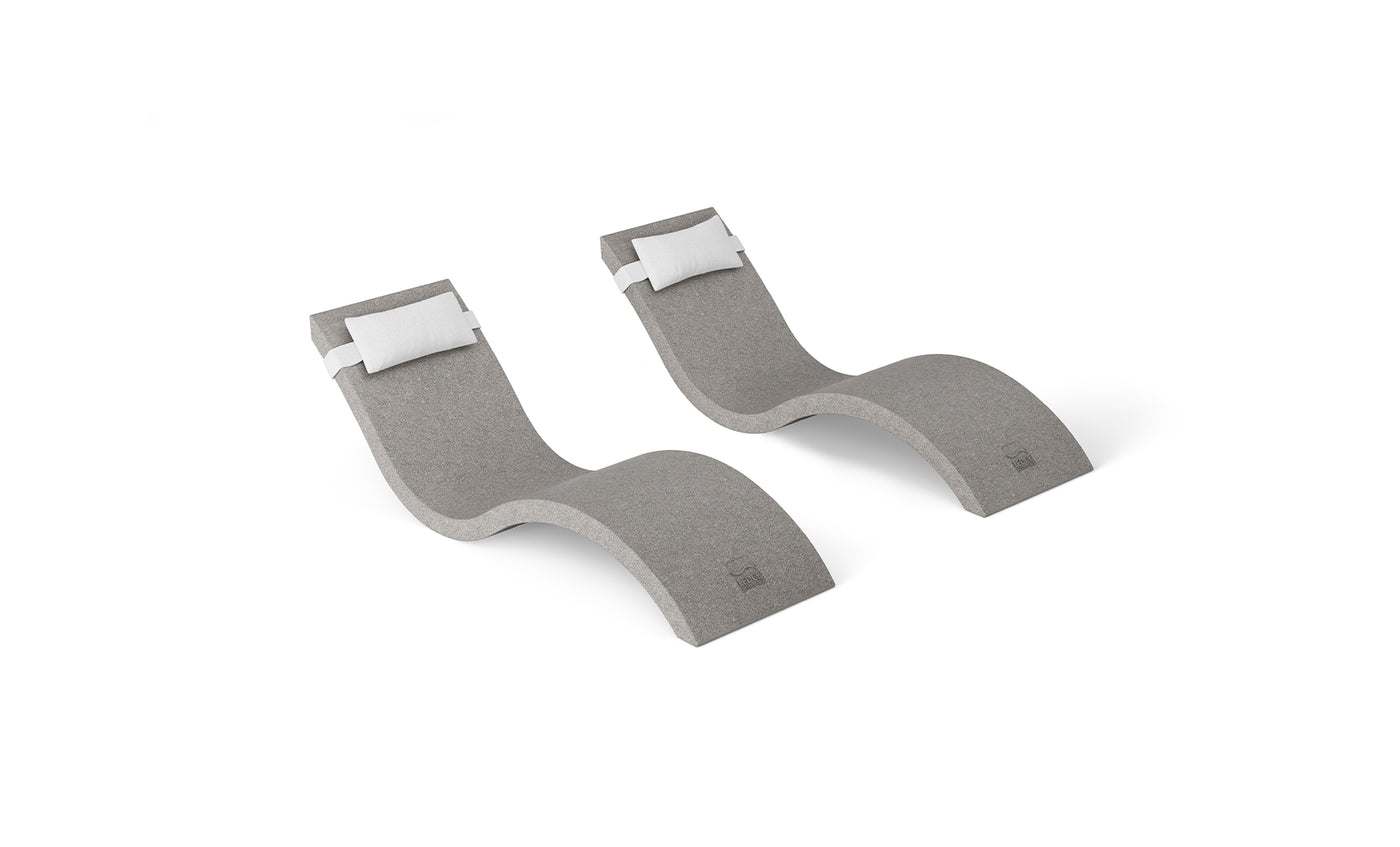 The Ledge Lounger Outdoor Escape In-Pool Furniture Bundle features two modern, gray wave-shaped chaise lounge chairs with integrated white headrest pillows. These sleekly designed chairs, set against a plain white background, offer smooth curves for a contemporary look.