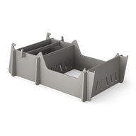 A gray, rectangular Signature Chair Riser by Ledge Lounger with vertical slits and pointed corner supports sits on a white background, ideal for organizing essentials during outdoor activities.