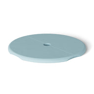The Ledge Lounger Signature Side Table Lid with Umbrella Hole is round and light blue, featuring a flat surface and small central hole. Its ergonomic indents and shadows give it an elevated look, while UV resistance makes it ideal for poolside use.