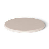 A round, flat, beige ceramic coaster with a small notch on one side rests on a white surface, enhancing your Ledge Lounger Signature Side Table Lid. Its UV-resistant finish ensures durability, making it ideal for any setting.