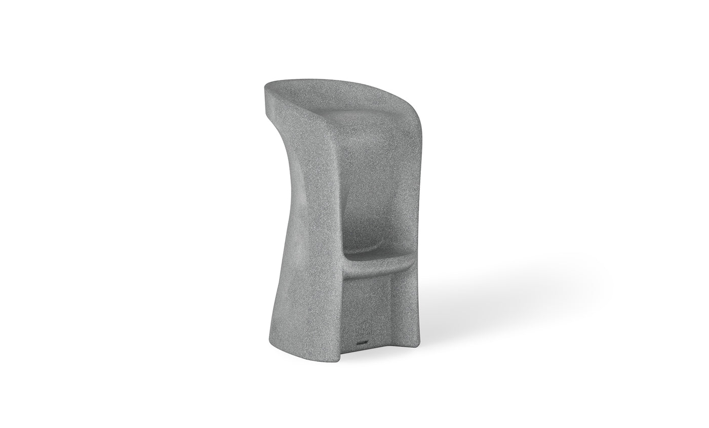Introducing the Signature Barstool Bar Height by Ledge Lounger: a modern minimalist gray stool with a high backrest, cylindrical form, and stone-like texture. Its widened base and integrated footrest ensure support, while the curved seat is perfect for poolside seating during outdoor entertaining.