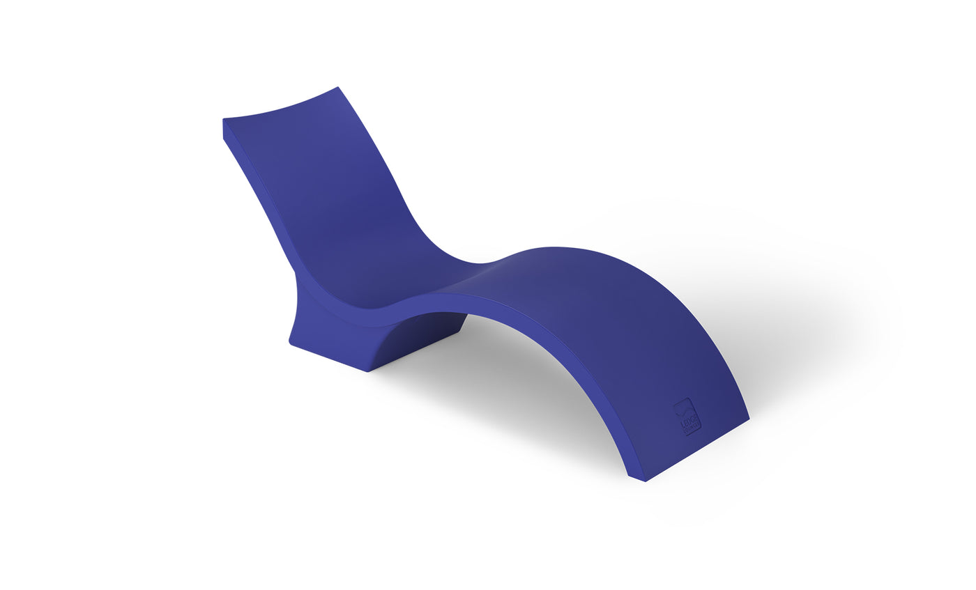 The Signature Chaise Deep by Ledge Lounger is a sleek, modern lounge chair with a minimalist wave design in bold blue. Its smooth, curved form creates a contemporary look, perfect for relaxing on the tanning ledge or adding flair against a plain white background.