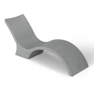 The Signature Chaise Deep by Ledge Lounger is a minimalist grey lounge chair with a wavy, modern design like a chaise lounge, featuring smooth surfaces and continuous curves for a sleek look. Its shown against a plain white background.