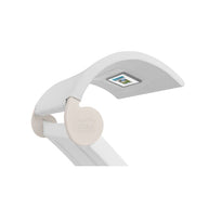 The Signature Chaise Shade by Ledge Lounger is a sleek, modern white LED desk lamp with an adjustable arm and curved head. Its visible light panel and circular hinge base stand out elegantly against a plain white background.