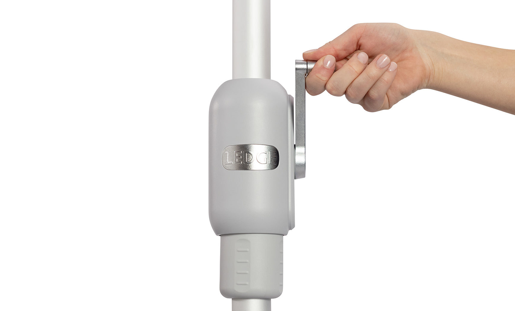 A person grips a metallic lever on a gray, cylindrical device from the 6.5 Square Signature 360° Tilt Umbrella by Ledge Lounger. Its rustproof frame, engraved with the brand name, stands out against the plain white background, highlighting its sleek design.