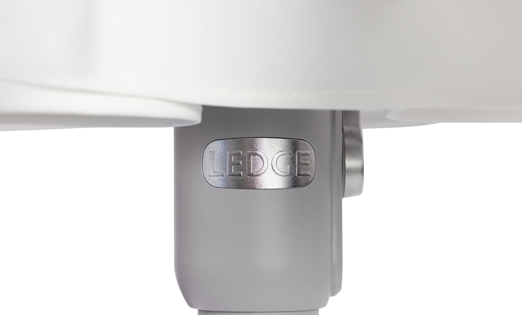 A close-up of a cylindrical metal component embossed with LEDCE evokes the durability of wind-resistant umbrellas. Connected to a larger white structure, it boasts a smooth light gray surface, reminiscent of the 6.5 Square Signature 360° Tilt Umbrella by Ledge Lounger.