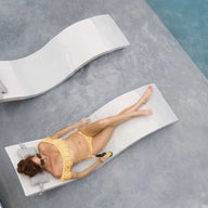 Friends in the backyard pool lounging on chaise and chatting on barstools.