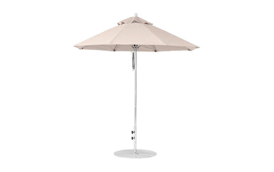 The Ledge Lounger Essential Fiberglass Umbrella features a 7.5 octagon canopy made of marine-grade fabrics and a metal cap, with a sturdy metal pole and round base. This wind-resistant model stands upright, showcasing evenly spaced panels when fully opened.
