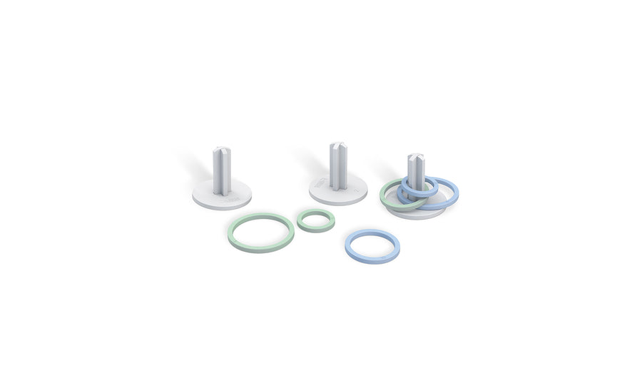 Three Ledge Lounger white cylindrical pegs on circular bases, surrounded by pastel blue and green rings, resemble a Ring Toss setup. Set against a plain white background, it invites a playful outdoor game experience.