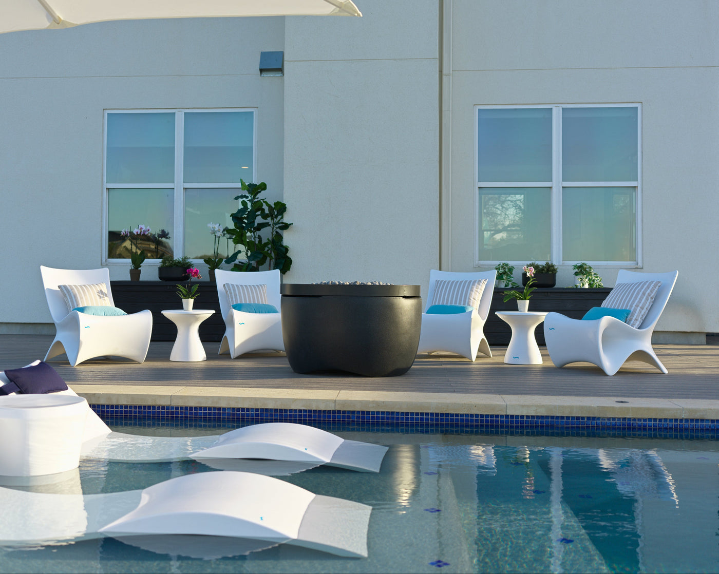 Outdoor seating area with white chairs and a pool in the foreground