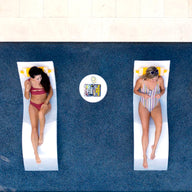 Two women lounging on in pool chaises with matching headrest pillows.