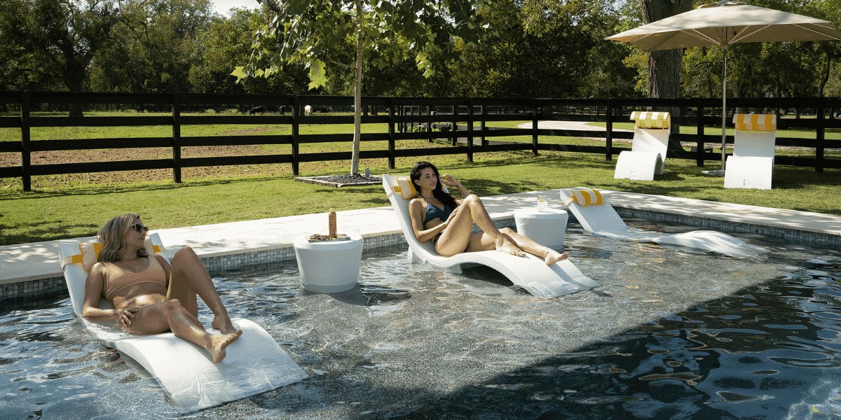 Woman relaxing on Ledge Signature Chaises on the pool ledge