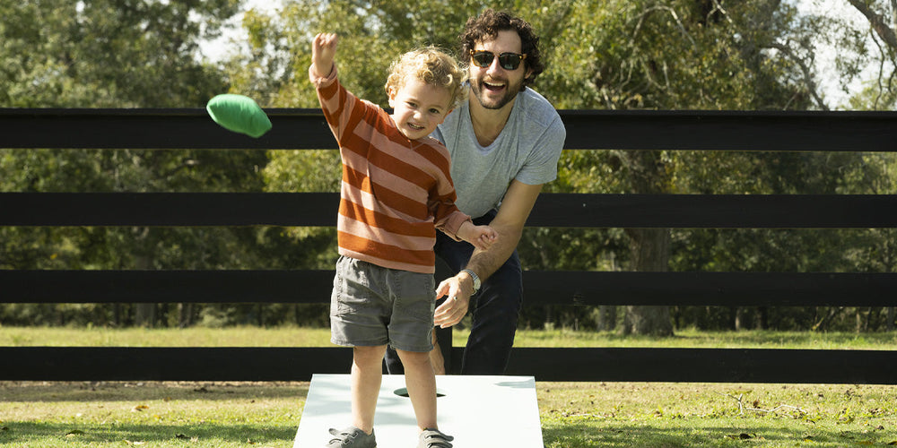 Kid and Dad playing cornhole in the backyard