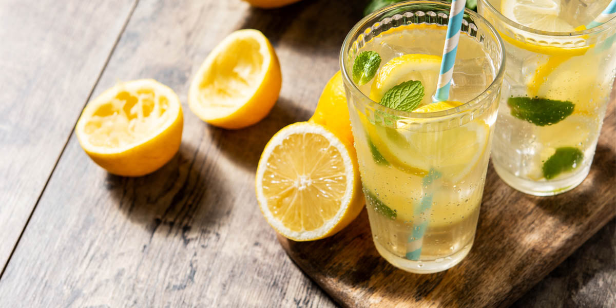 Glasses of lemonade next to sliced lemons
