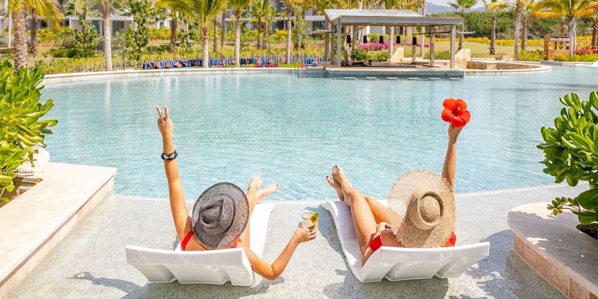 Woman celebrating their time by the pool, relaxing on Ledge Signature Chaises