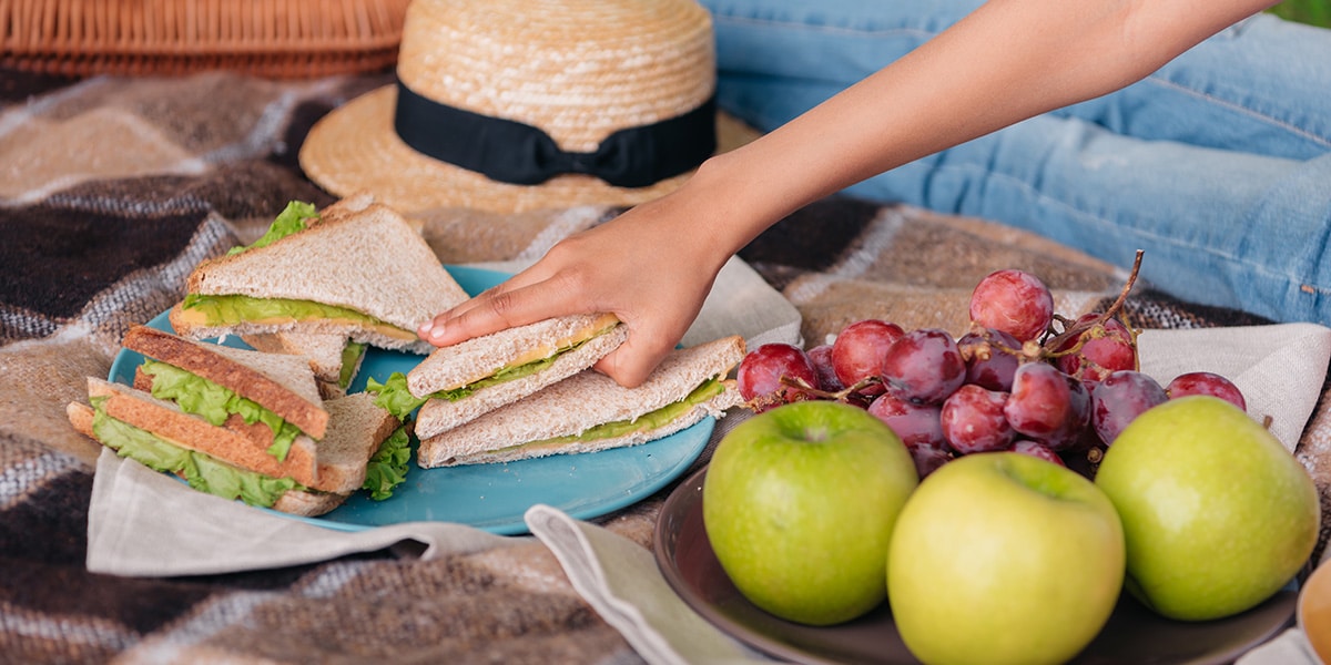 Picnic food, sandwiches, green apples, and red grapes