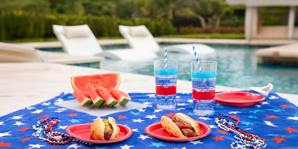 Fourth of July spread with tablecloth, hot dogs, and watermelon in front of the pool