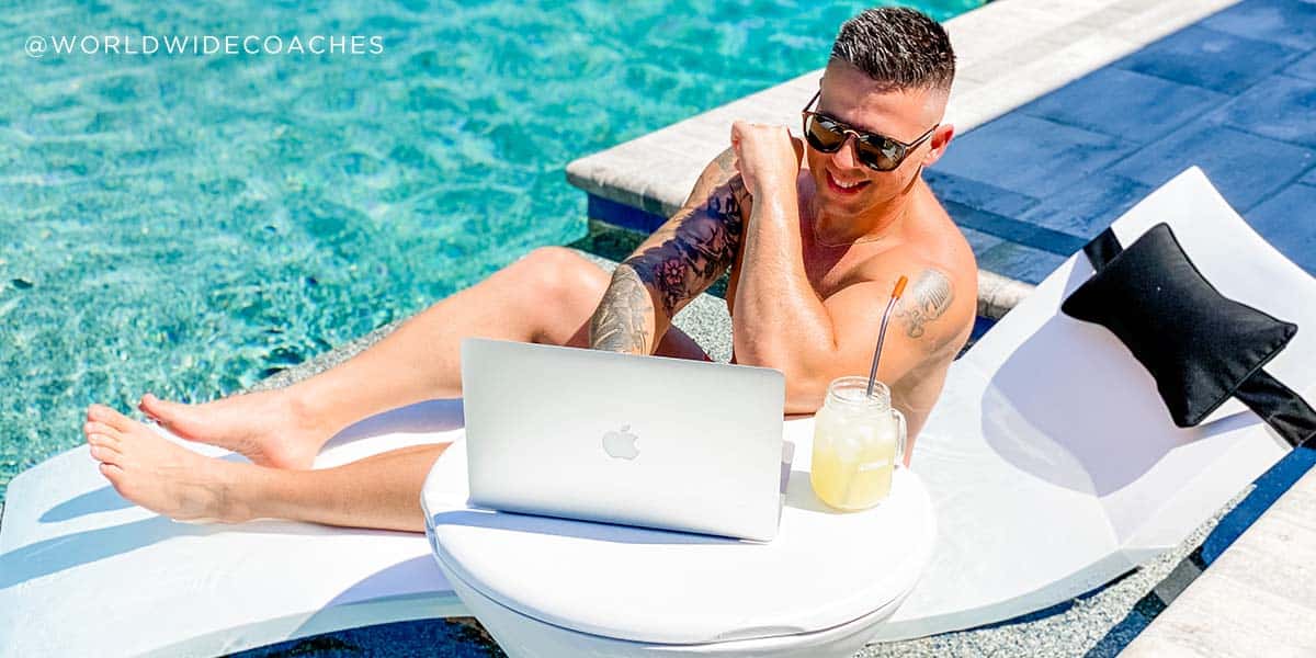 Man working on laptop from his seat on the pool ledge